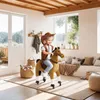 A young girl dressed as a cowboy rides a toy horse in a living room. Náhled obrázku produktu