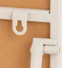 A close-up view of a white metal frame with a hanging hook and a support bracket. Produktbild-Vorschau