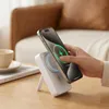 A hand is holding a smartphone over a white wireless charger on a wooden table. Produktbild-Vorschau