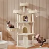Three cats interact with a multi-level cat tree in a room with beige, vertical-paneled walls. Podgląd zdjęcia produktu
