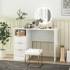 A white vanity desk with drawers and a round mirror with LED lights, a white stool, and a potted plant. Náhled obrázku produktu