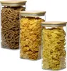 Three glass storage containers filled with different types of pasta and cereal, with wooden lids. Produktbild-Vorschau