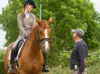 A woman riding a horse is being instructed by a man. Náhľad obrázku produktu