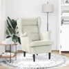 A cream-colored armchair is placed in a well-lit room with a plant and a side table. Náhľad obrázku produktu