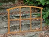 A rusty metal window frame rests on stone steps outdoors, surrounded by fallen leaves and greenery. Produktbild-Vorschau