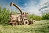 A wooden model of a combine harvester in a field of tall green grass under a blue sky with clouds. Podgląd zdjęcia produktu