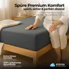 A person sitting on a bed with a fitted sheet. Produktbild-Vorschau