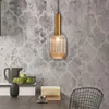 A pendant light hangs above a table with a pitcher, apples, books, and a chair in the background. Produktbild-Vorschau