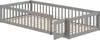 A grey wooden toddler bed with a slatted base and a partial railing. Náhled obrázku produktu