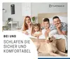 A family and their dog are relaxing on a bed in a bedroom. Produktbild-Vorschau