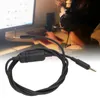 A person wearing headphones is in the background, looking at a computer screen. A black headset cable with an inline control is in the foreground. Podgląd zdjęcia produktu