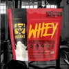 A bag of Mutant Whey protein powder is displayed in a gym setting. Produktbild-Vorschau