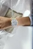 A person wearing a clear Casio G-Shock watch on their wrist, with part of a white jacket visible. Voir les images du produit