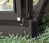 A close-up view of the corner of a dark grey aluminum greenhouse frame, resting on green grass. Produktbild-Vorschau
