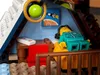 A LEGO minifigure sleeping in a bed inside a small room, with a painting of a rocket and moon on the wall. Podgląd zdjęcia produktu