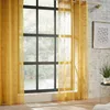 A yellow sheer curtain hangs in front of a large window, with sunlight streaming through. Podgląd zdjęcia produktu