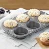 A muffin tin with several blueberry muffins, some in the tin and one next to it on a napkin. Anteprima dell’immagine prodotto