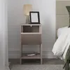 A bedside table with a lamp, e-reader, and phone, next to a bed. Produktbild-Vorschau