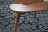 A close-up of a wooden coffee table leg and tabletop, resting on a patterned rug. Produktbild-Vorschau
