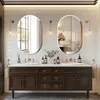 A modern bathroom with a double vanity, two oval mirrors, and decorative lighting. Podgląd zdjęcia produktu
