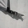 A close-up view of a strap and buckle attached to a gray fabric, likely part of an outdoor cover or shelter, secured to a textured surface with a suction cup. Náhled obrázku produktu