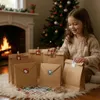 A young girl is sitting on the floor in front of a fireplace and a Christmas tree, assembling an advent calendar with brown paper bags. Produktbild-Vorschau
