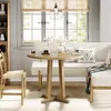 A dining set with a round table and chairs in a bright, airy room with a large window. Produktbild-Vorschau