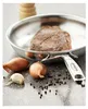 A steak is being seared in a frying pan, with shallots, garlic, and peppercorns nearby. Náhled obrázku produktu