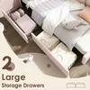 A close-up view of a pink upholstered bed frame with two open storage drawers filled with linens and stuffed animals. Podgląd zdjęcia produktu