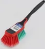A cleaning brush with red and green bristles and a black handle, set against a light gray background. Produktbild-Vorschau