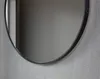 A close-up of a round mirror with a black frame hanging on a textured gray wall. Anteprima dell’immagine prodotto