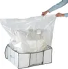 A person is holding the top of a clear vacuum seal bag that contains bedding, which is placed inside a fabric storage box. Produktbild-Vorschau