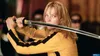 A woman in a yellow tracksuit holds a sword. Produktbild-Vorschau