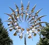A kinetic wind sculpture made of stainless steel, set against a clear blue sky with some trees in the background. Anteprima dell’immagine prodotto
