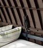 Close-up view of the interior of a brown storage box, showing a gas strut mechanism and a striped cushion. Podgląd zdjęcia produktu