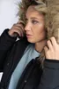 A woman wearing a black winter jacket with a fur-lined hood. Produktbild-Vorschau