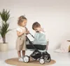 Two young children playing with a doll stroller indoors. Produktbild-Vorschau