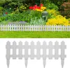 A white picket fence border in front of a garden with flowers. Náhľad obrázku produktu
