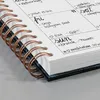 A close-up view of an open spiral-bound notebook with handwritten notes and drawings on the pages. Náhľad obrázku produktu