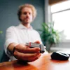 A person holding a USB drive in front of a desk with a computer mouse. Náhľad obrázku produktu
