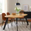 A dining table with chairs set up in a room, with a sideboard and artwork in the background. Produktbild-Vorschau