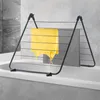 A black metal clothes drying rack is placed over a bathtub, with a yellow garment and a gray towel hanging on it. Voir les images du produit