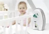 A baby monitor is placed on a table next to a crib with a baby in it. Produktbild-Vorschau
