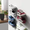 Several pairs of sneakers are displayed on a white wall, mounted on clear shelves. Produktbild-Vorschau