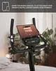 Close-up of an exercise bike's handlebars and console, with a tablet mounted on it. Produktbild-Vorschau
