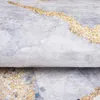 A close-up view of a folded rug with a marble abstract pattern in gray and gold. Produktbild-Vorschau