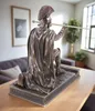 A bronze-colored statue of a Roman centurion kneeling with a spear, placed on a wooden table in a living room setting. Produktbild-Vorschau