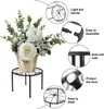 A black metal plant stand with a floral arrangement in a gold pot, surrounded by feature callouts. Produktbild-Vorschau