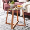 A small round side table with a glass top and wooden legs, placed on a patterned rug next to a sofa. Anteprima dell’immagine prodotto