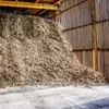 A large pile of wood chips inside a structure with wooden walls and ceiling. Produktbild-Vorschau